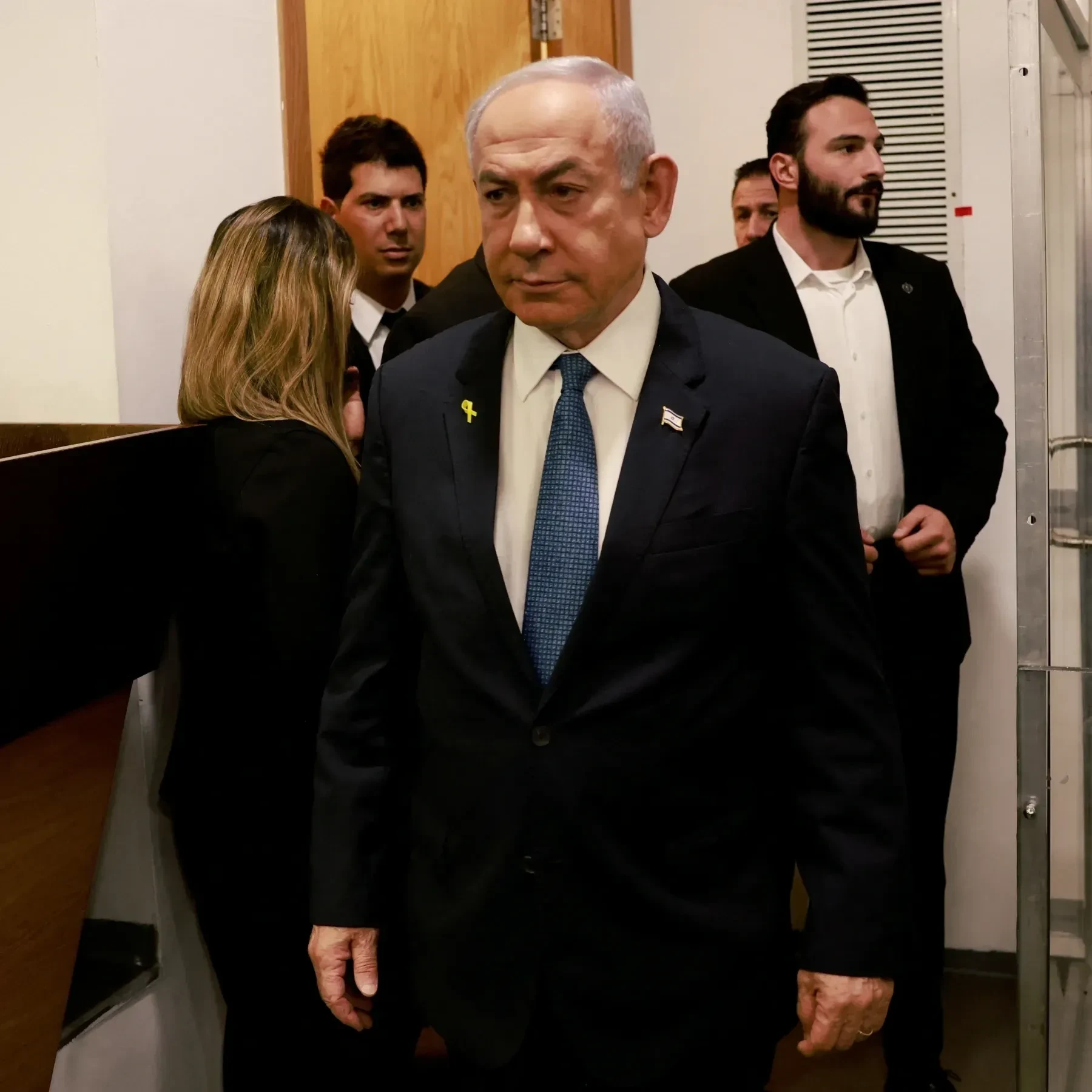 Senior official walking with security staff indoors